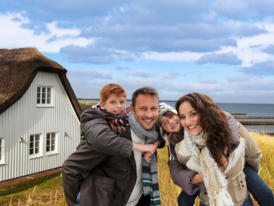 Familie im Winter vor einem Ferienhaus an der Nordsee